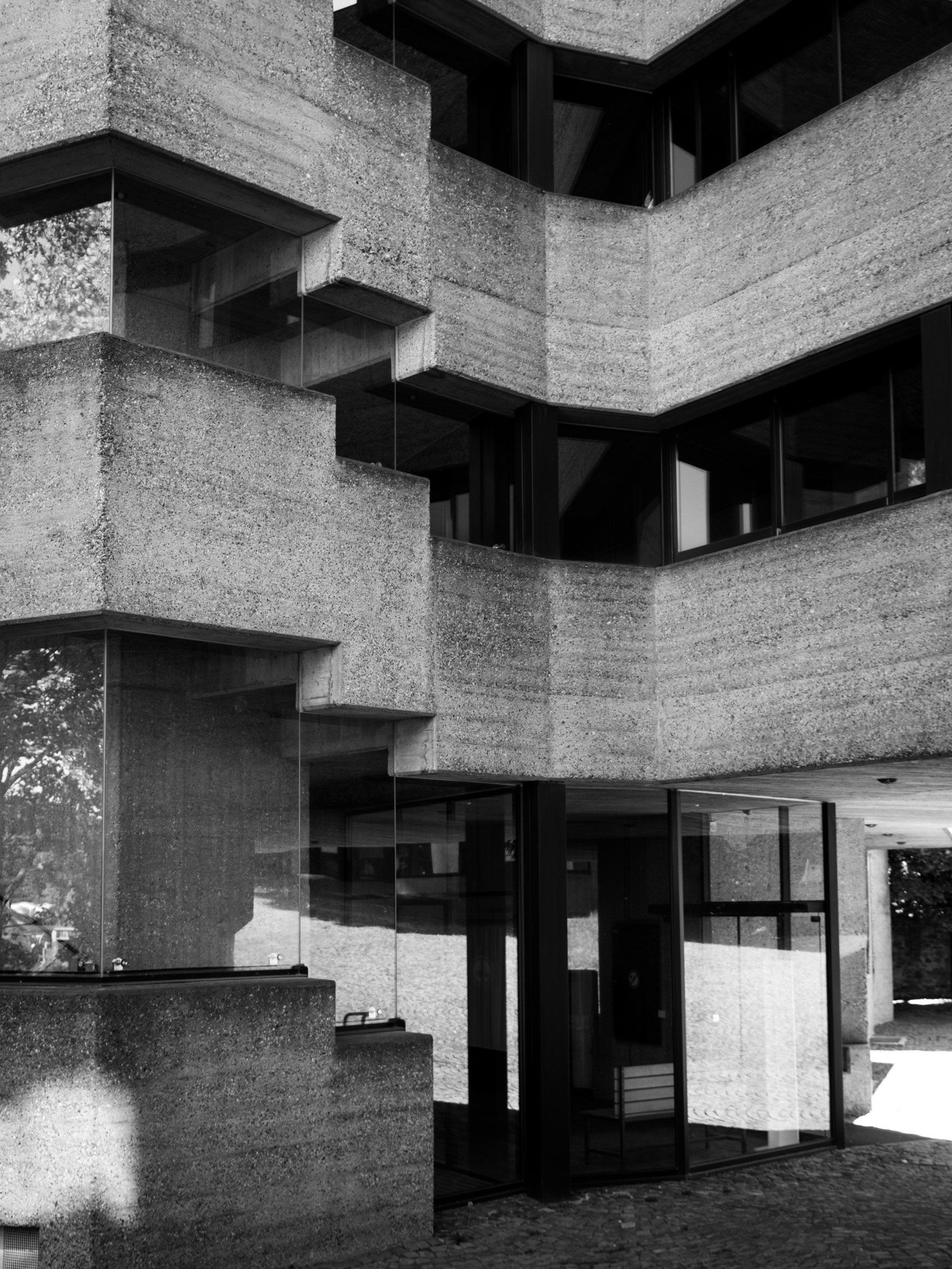Glass-fronted balcony corner detail on the concrete facade