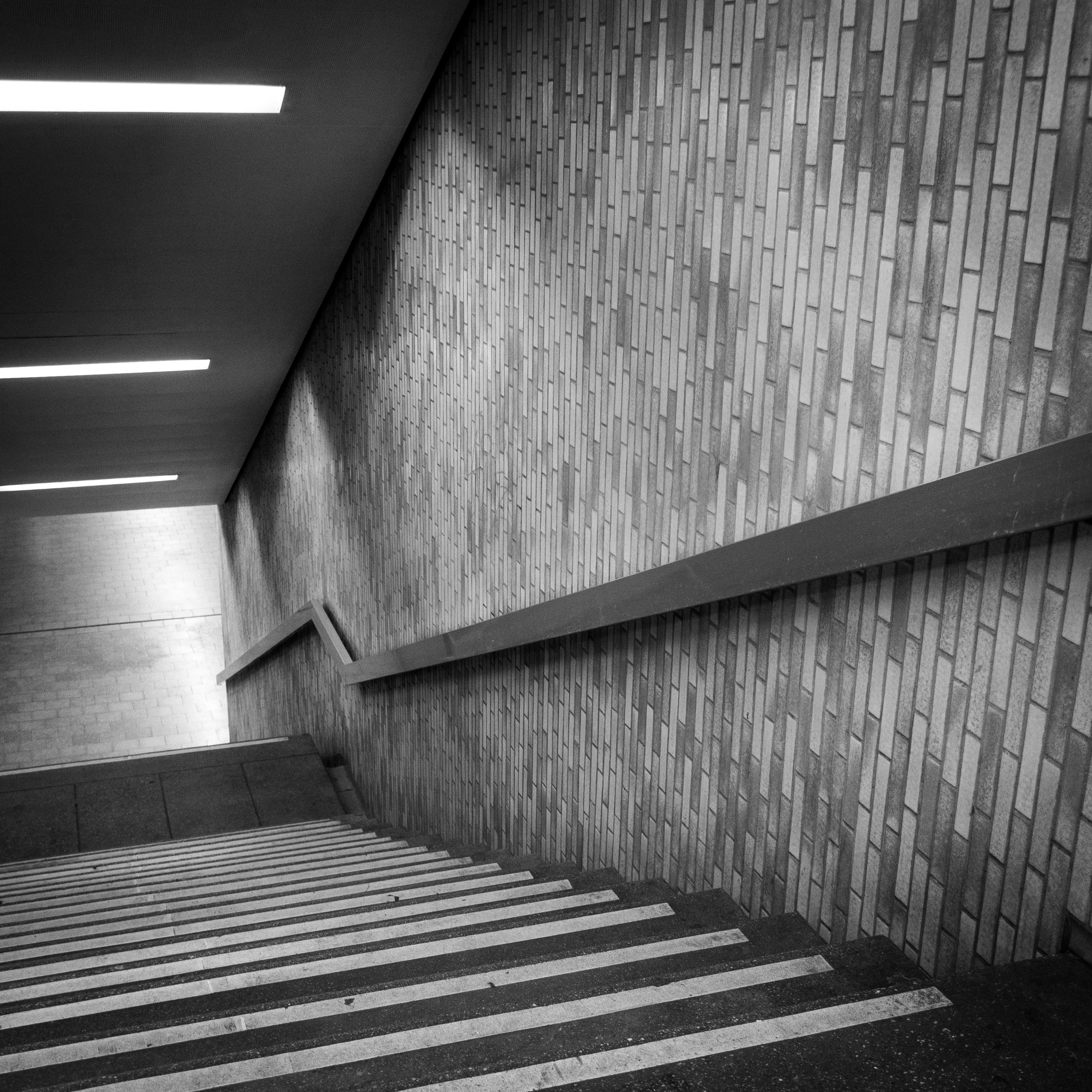 Stairwell with diagonal tiled wall and handrail, Lohsestraße underground station, Cologne