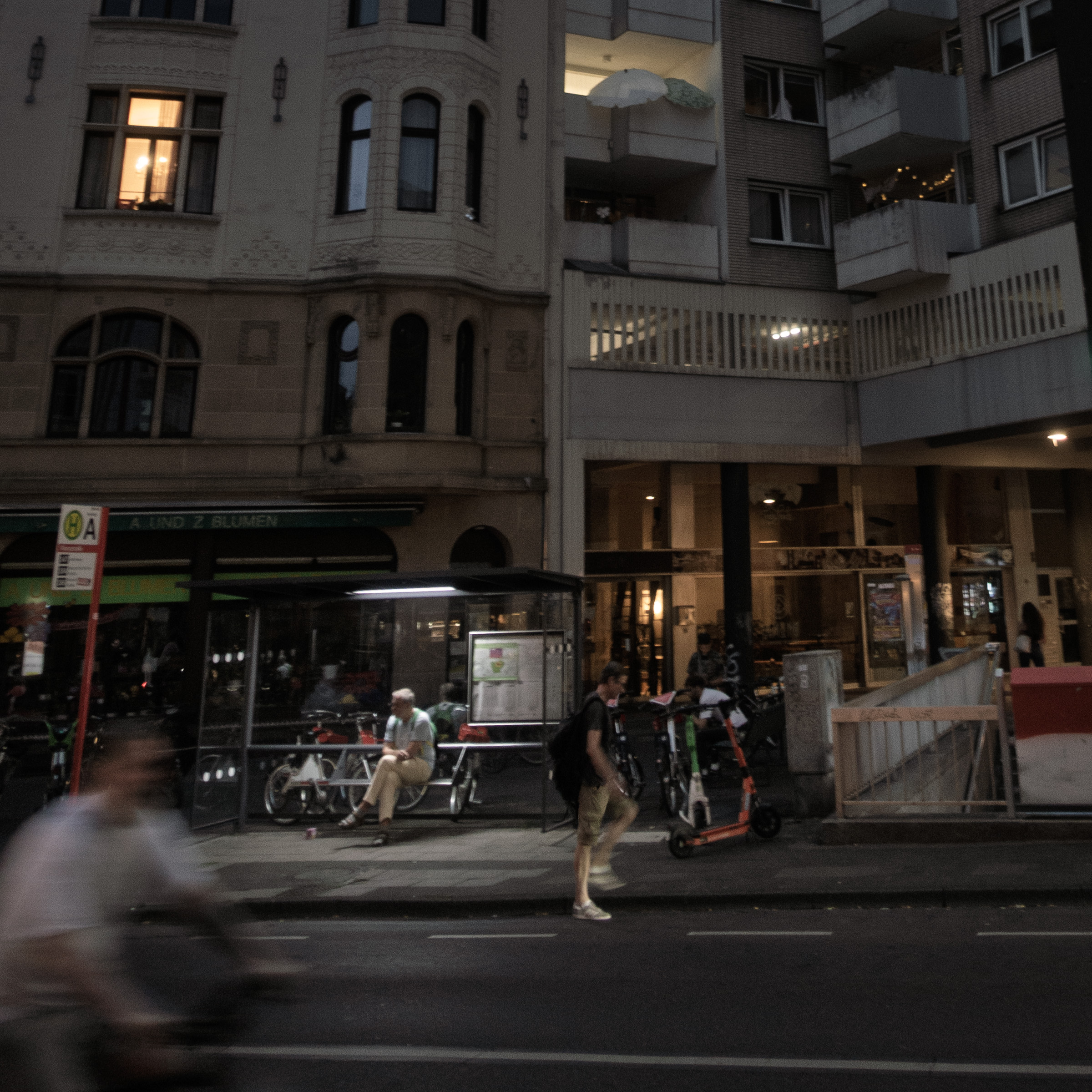 Nighttime street scene with a bus stop and passersby, Florastraße, Nippes, Cologne