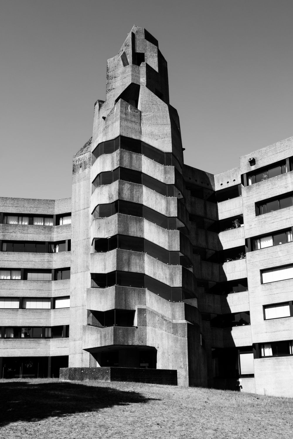 Full view of the crystalline concrete tower of Rathaus Bensberg with courtyard and tree