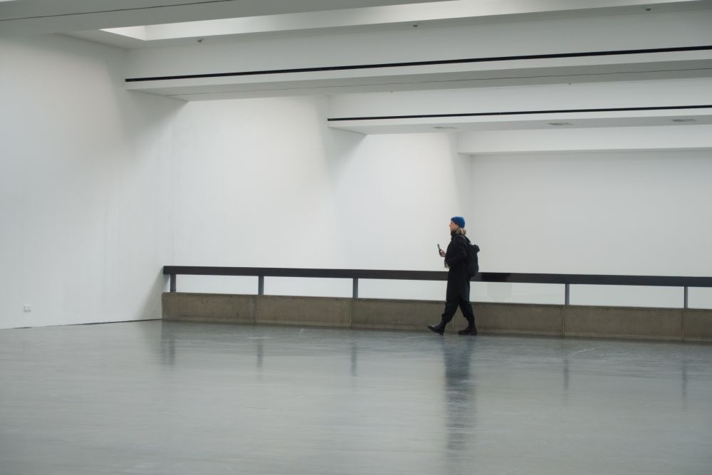 Visitor walking through empty gallery space with concrete balustrade, Kunsthalle Düsseldorf