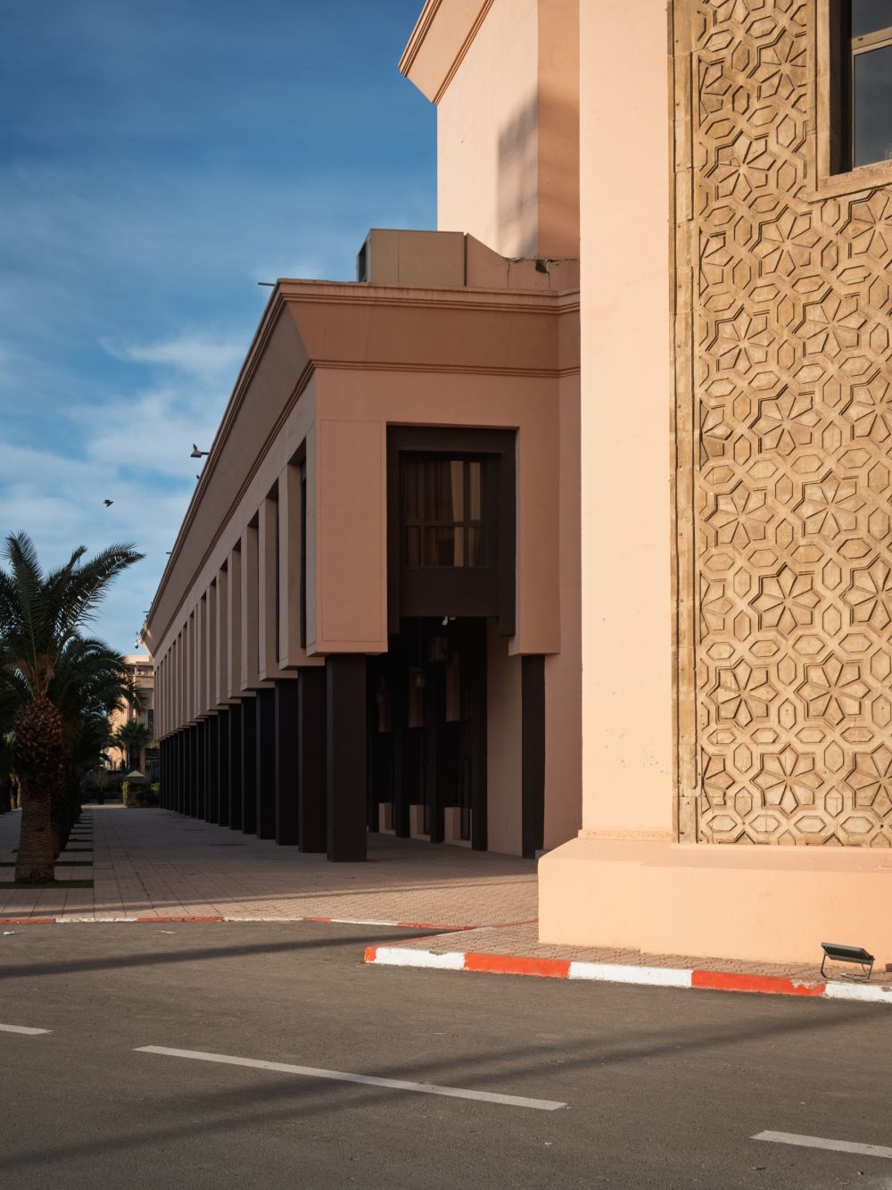 Repetitive columns and intricate Moroccan reliefs at Palais des Congrès, Marrakech, casting long shadows in the late afternoon light.