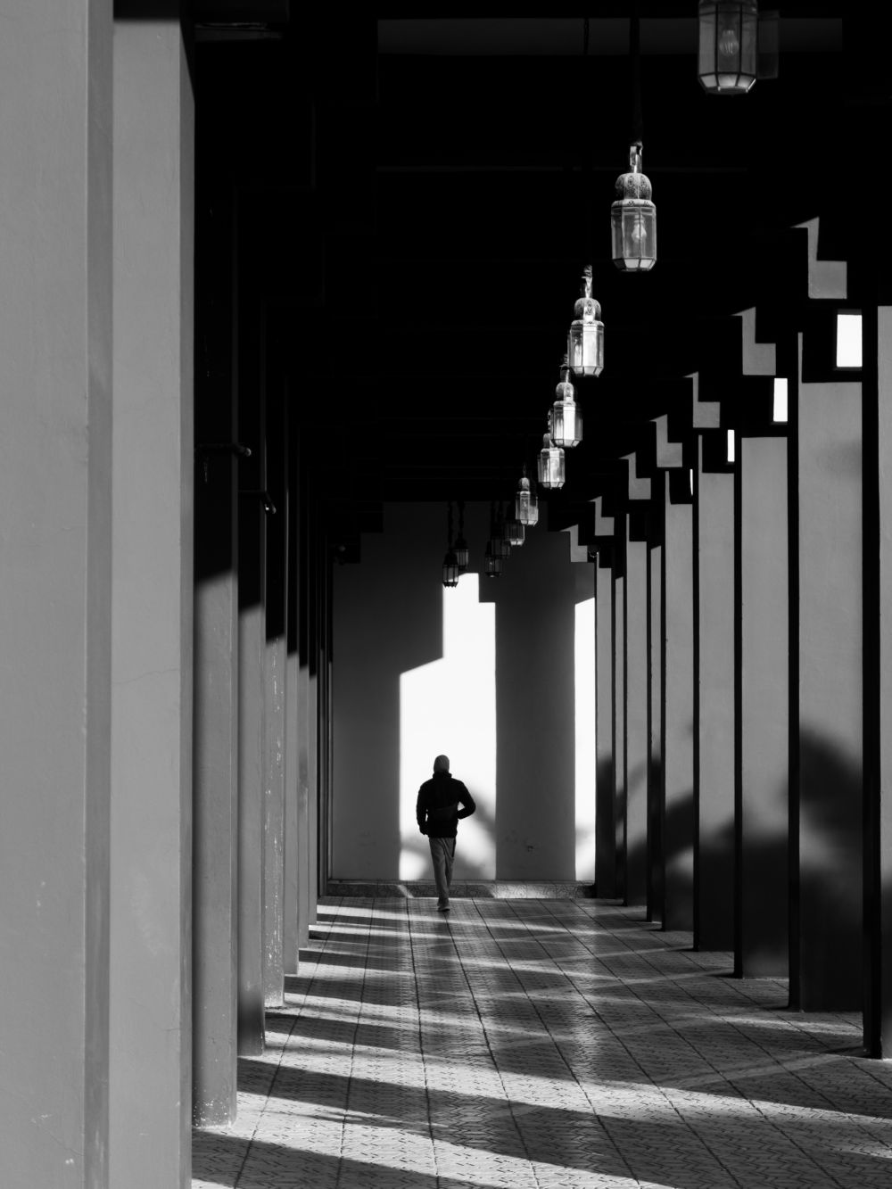 Black and white image of a corridor at Palais des Congrès, with lanterns and a solitary figure adding depth.