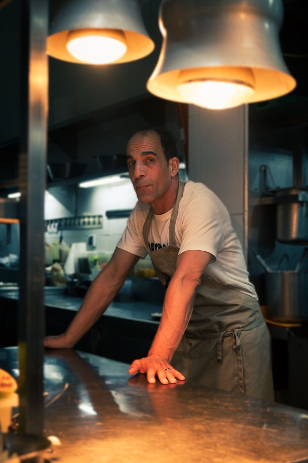 Head chef leaning over the pass in the professional kitchen of La Trattoria Marrakech