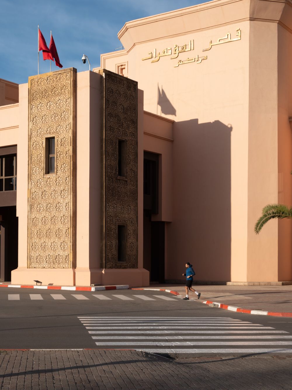 A jogger passing by Palais des Congrès, Marrakech, adding a dynamic element to the static architecture.