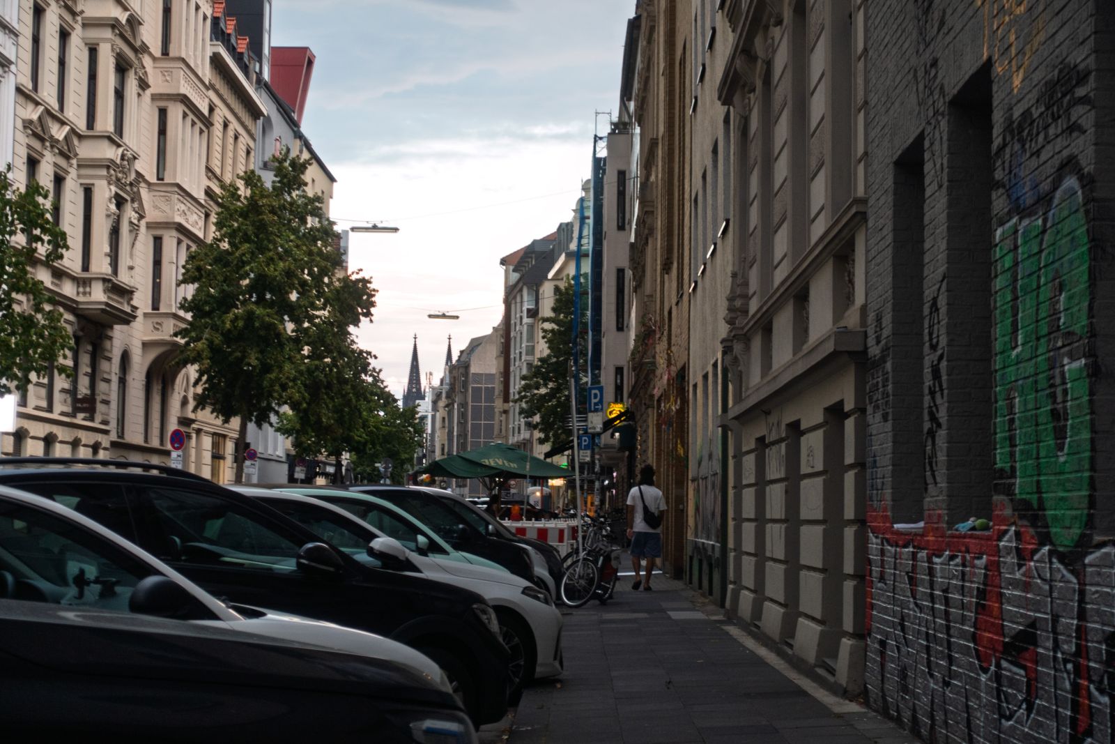 Narrow street in Ehrenfeld, Cologne, with Cologne Cathedral's spires visible in the distance
