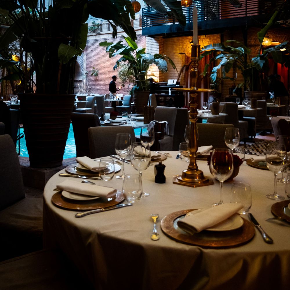 Elegantly set round dining table with candelabra and wine glasses at La Trattoria Marrakech